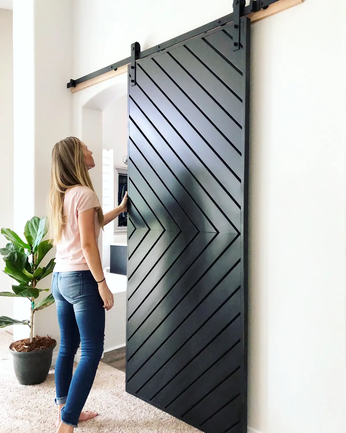 Large black chevron barn door mounted on a black track against a white wall
