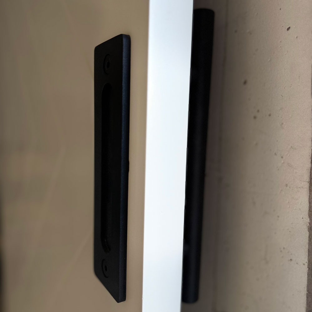 Side view of a black recessed pull and coordinated back-side barn-door grip