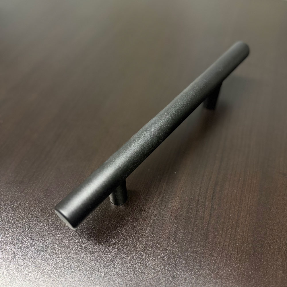 Brushed-metal tubular barn-door pull photographed from an angled view