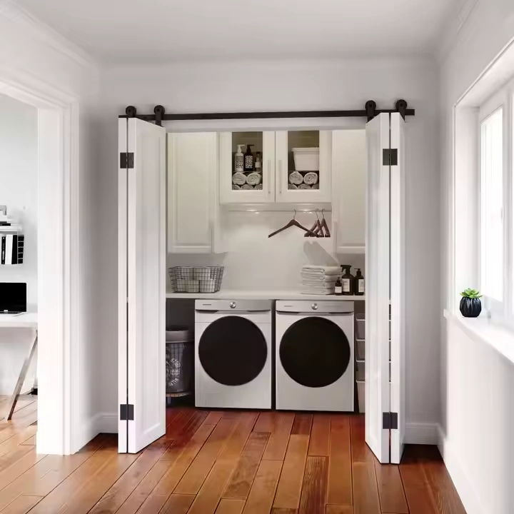 Pair of white bi-fold barn doors opened to reveal a laundry room