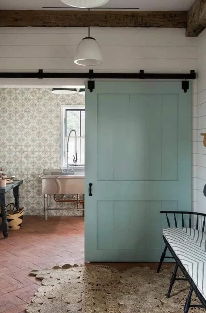 Light blue two-panel barn door sliding open beside a room with a sink
