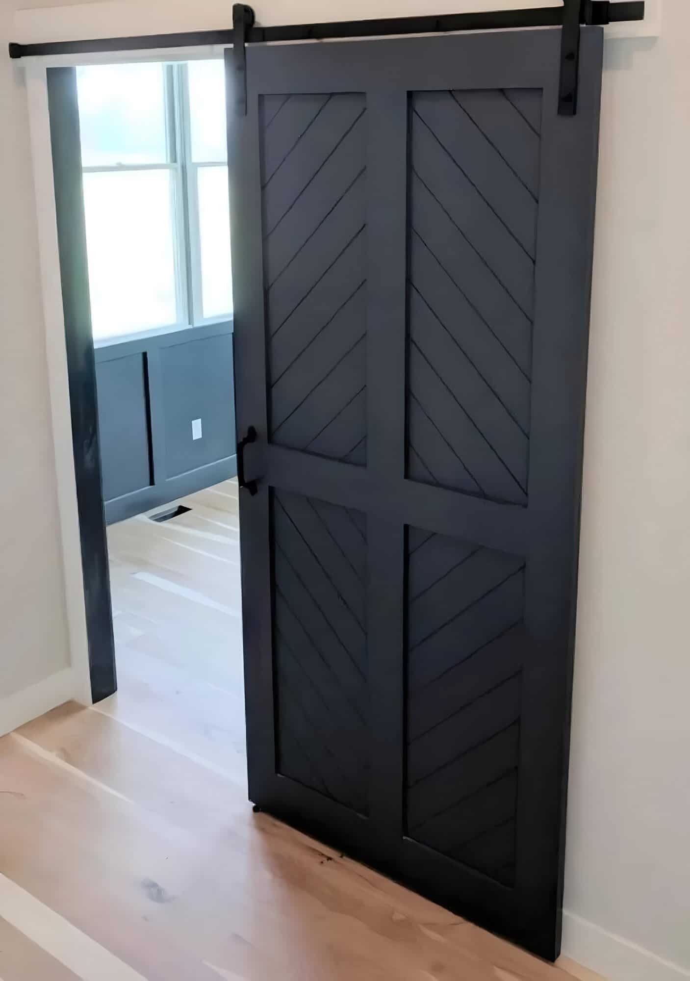 Dark gray barn door with four diagonal-slat panels in a modern interior