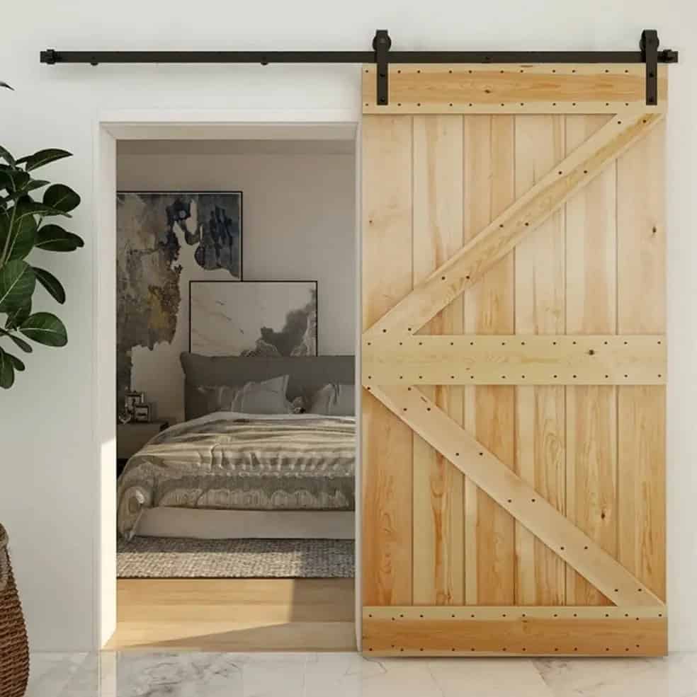 Light wood barn door with a K-brace design opening to a bedroom