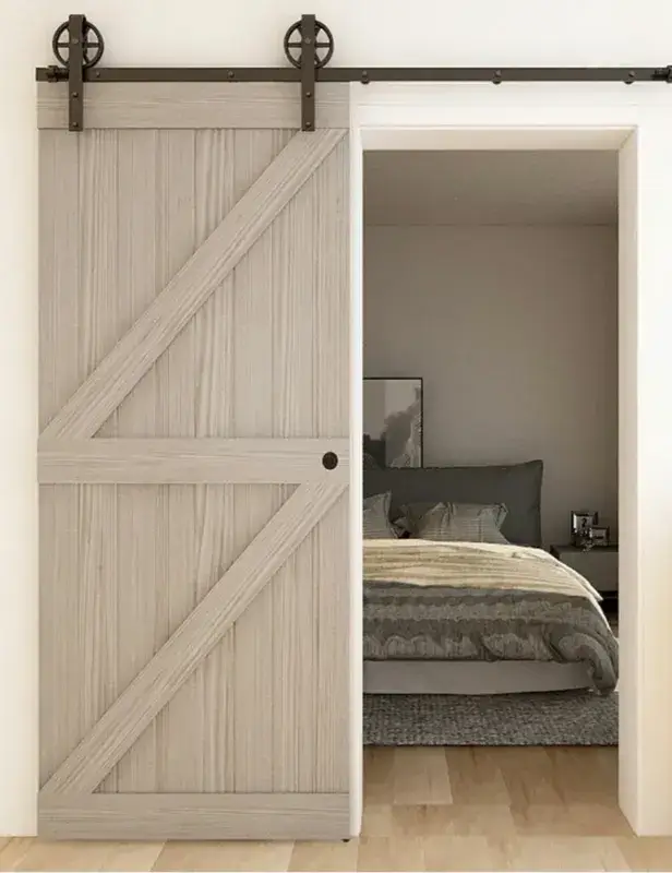Light wood barn door with double Z-braces partially open to a bedroom