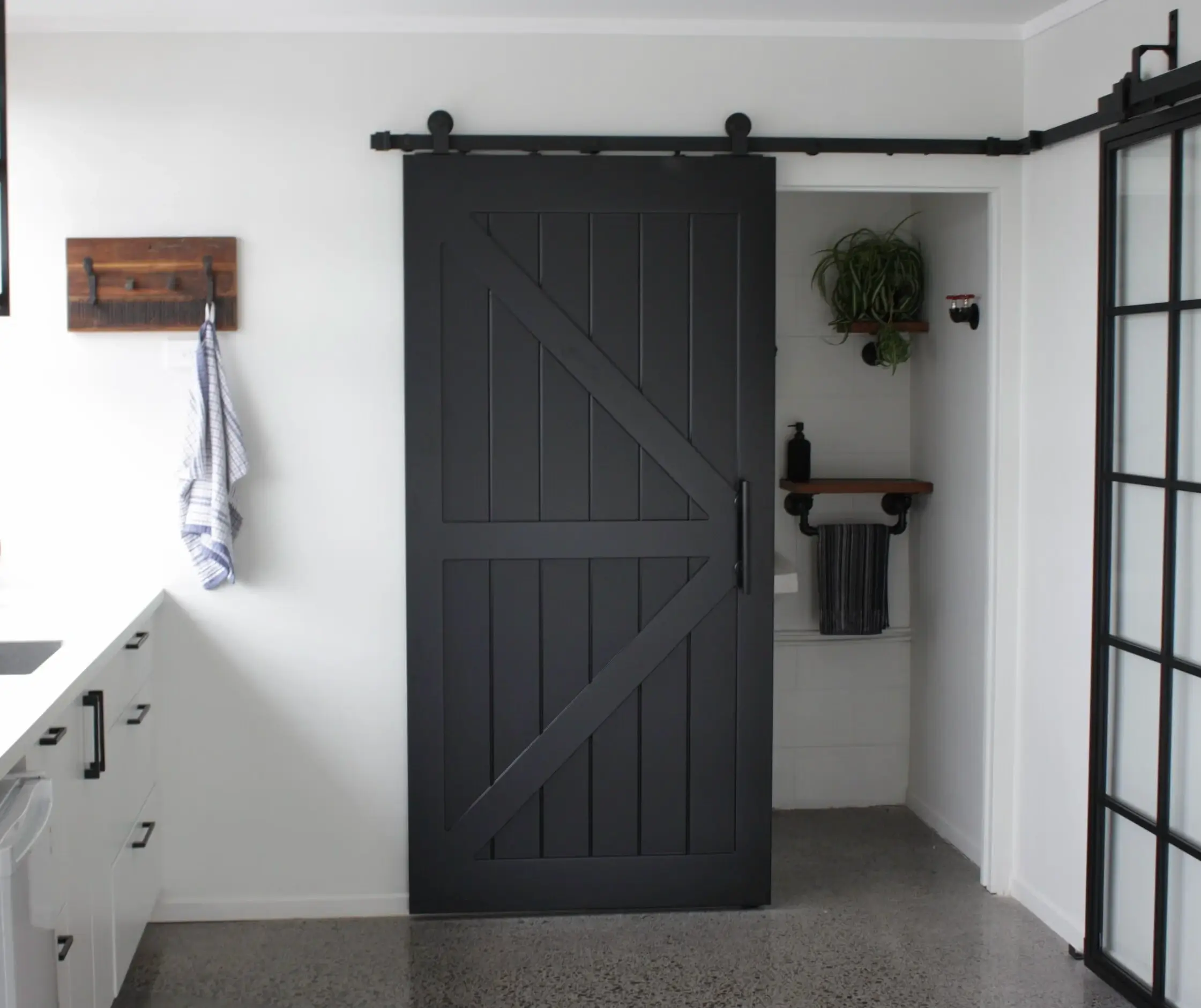 Black double Z-brace barn door beside a white storage cabinet