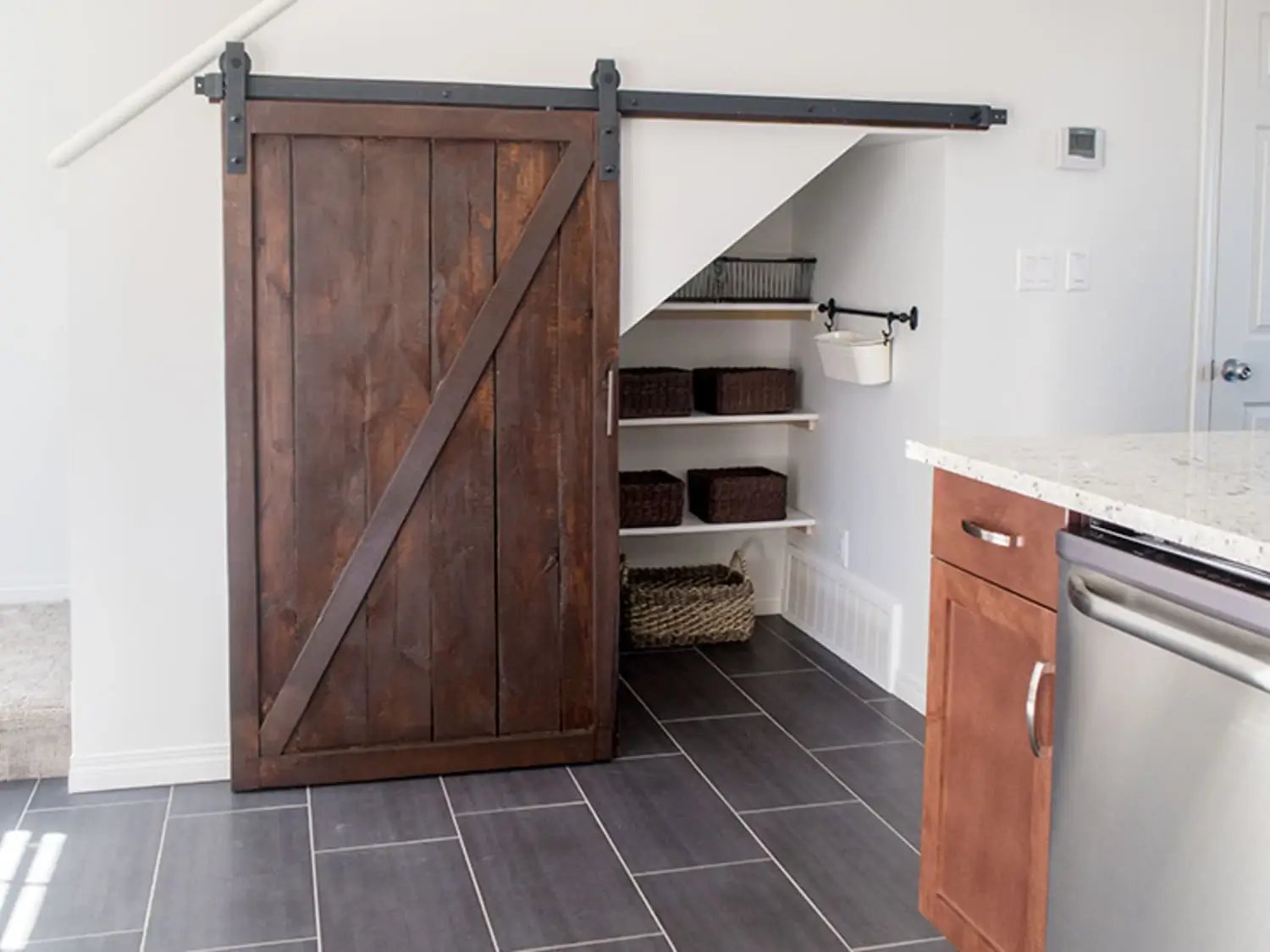 Dark wood diagonal-brace barn door opening to storage beneath a staircase