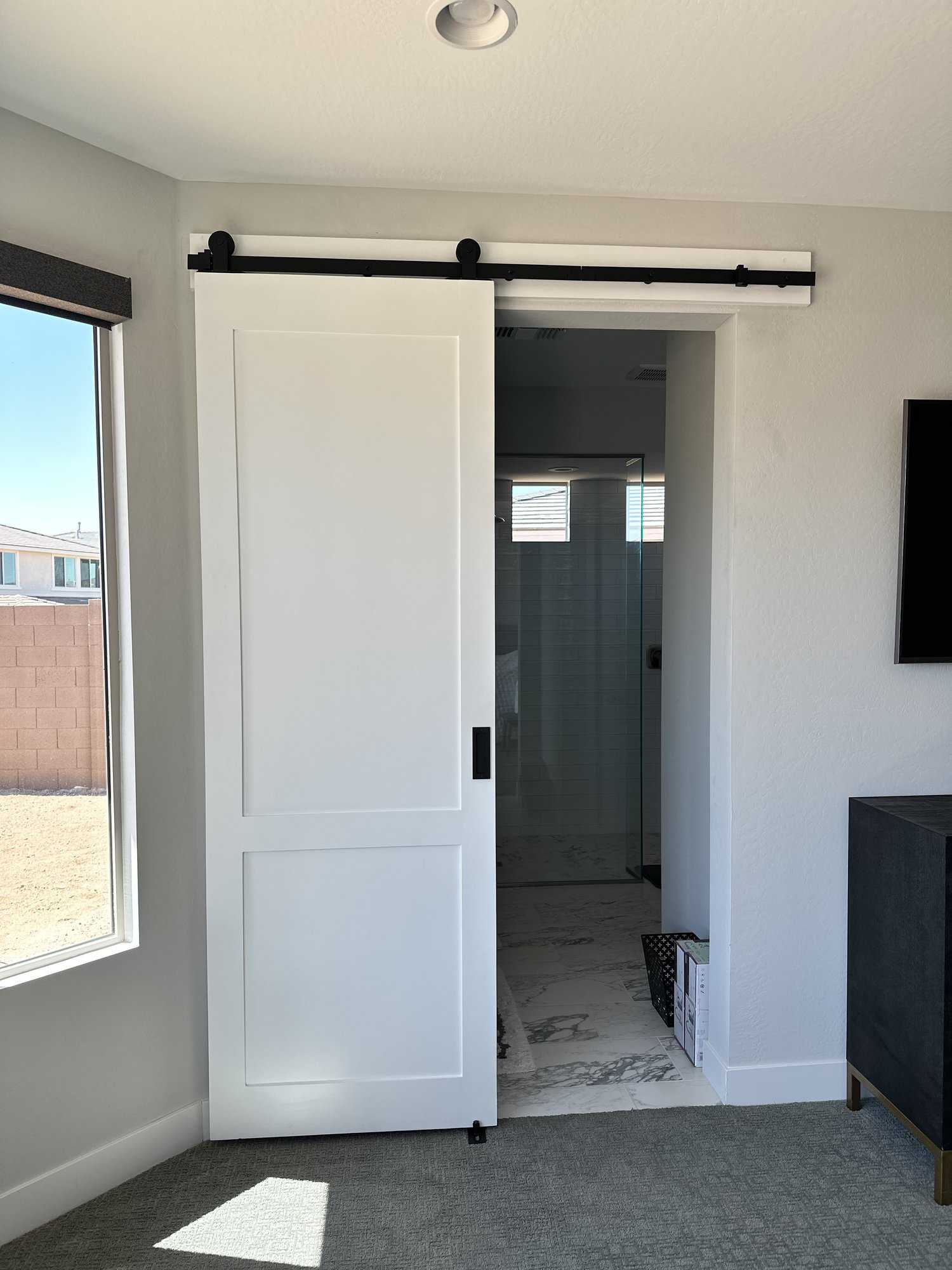 White two-panel sliding barn door partially covering a bathroom doorway