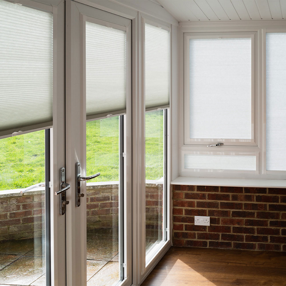 White cellular shades covering tall patio door windows