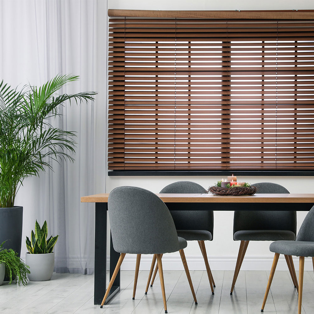 Brown faux wood blinds installed beside a dining area