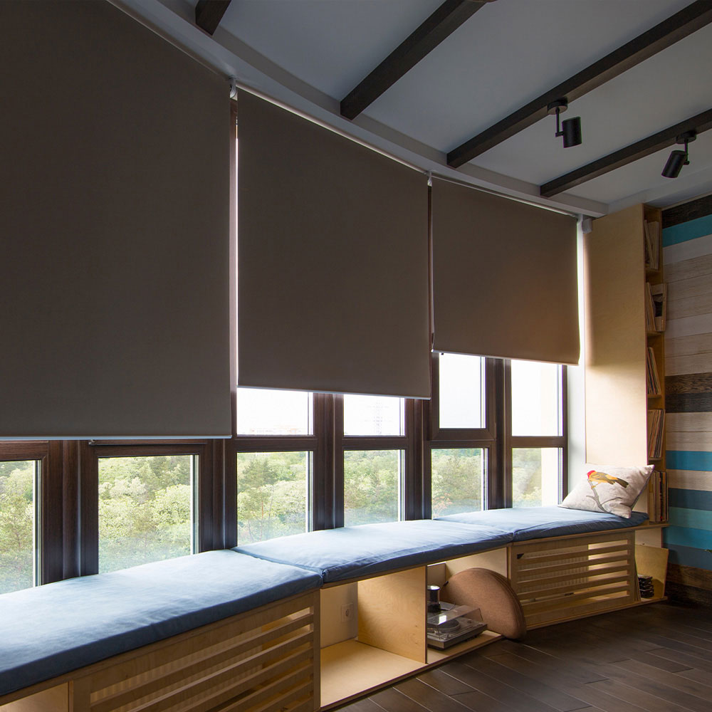 Dark roller shades above a cushioned window seat