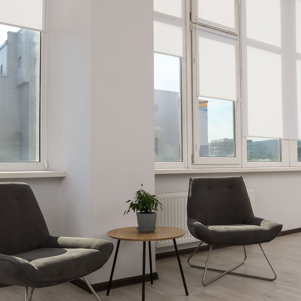 White roller shades diffusing daylight in a lounge area