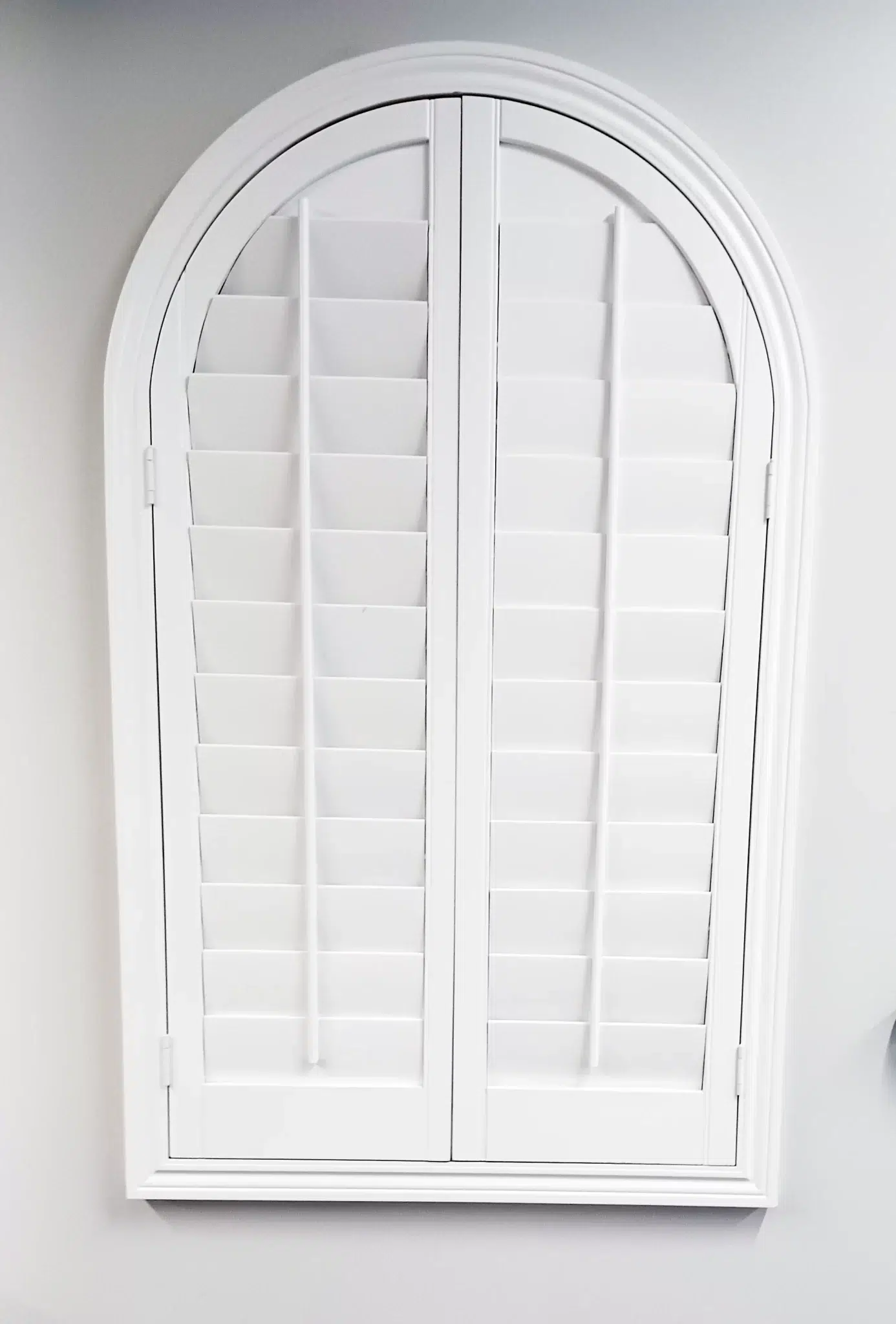 White plantation shutters shaped to fit an arched window