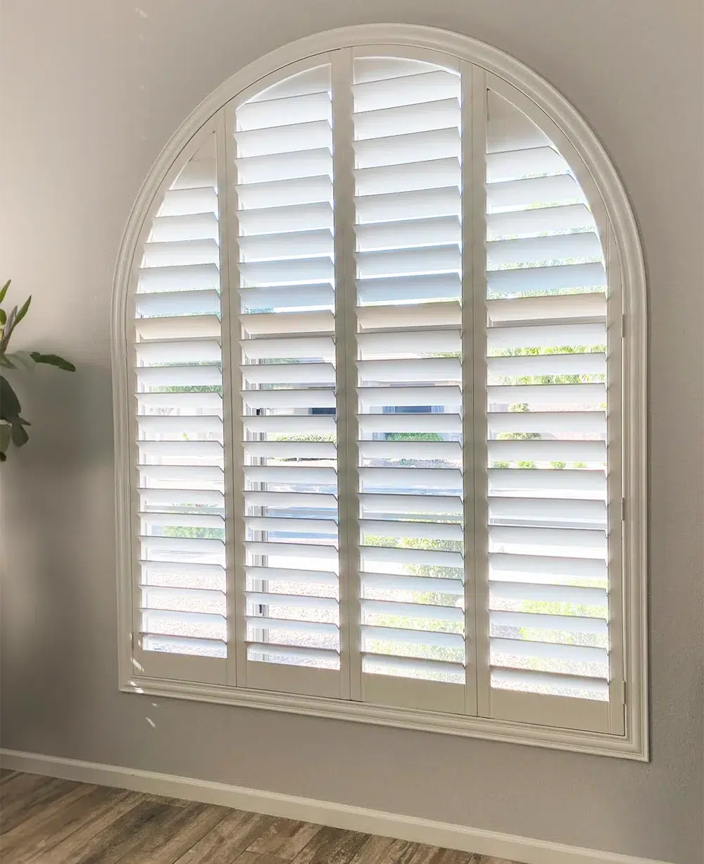 White plantation shutters custom fitted to a tall arched window