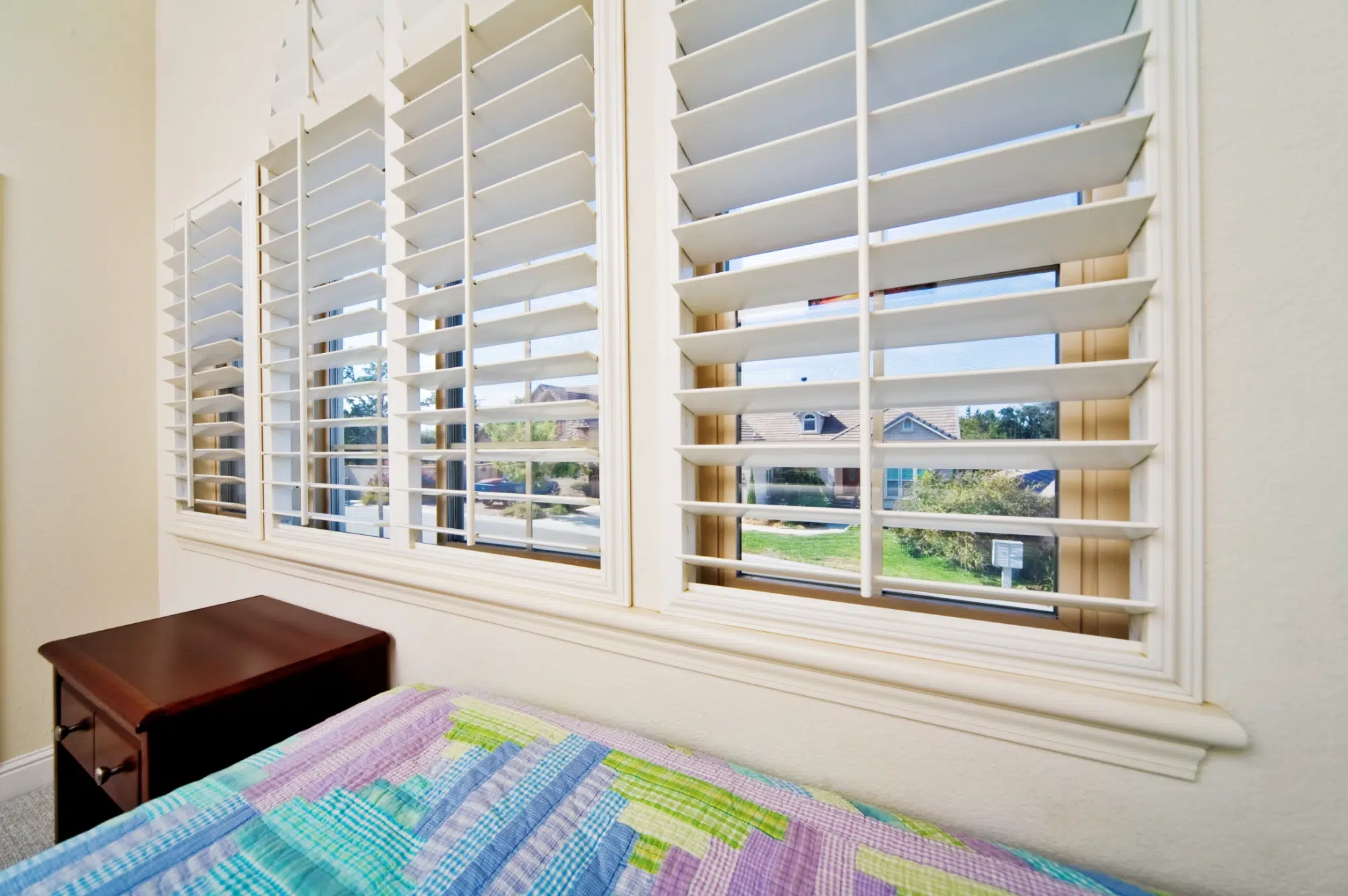 White plantation shutters installed in a softly furnished bedroom