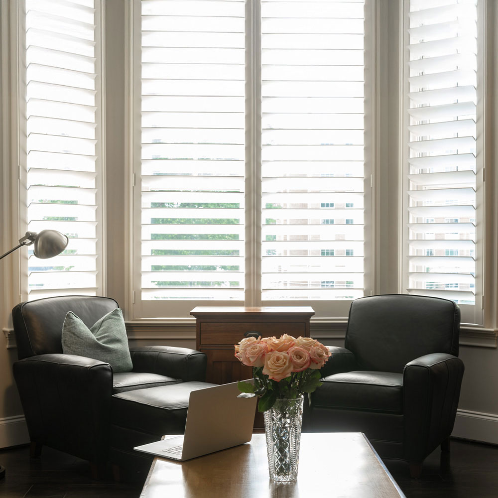 White plantation shutters across a bright sitting room bay window