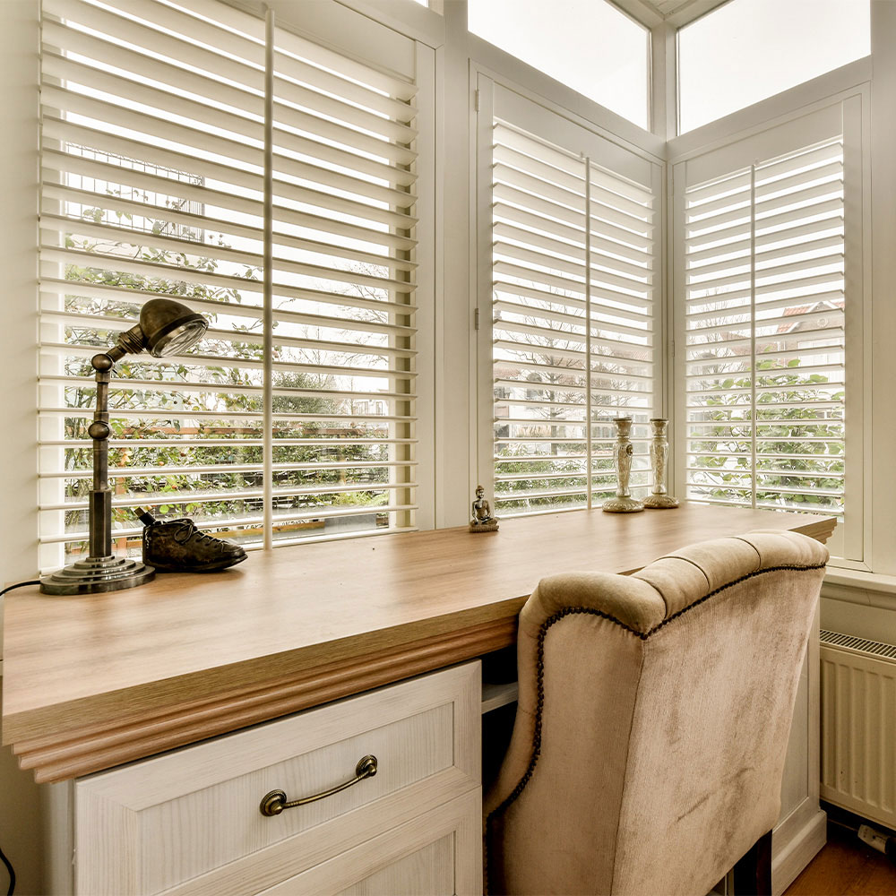 White shutters above a corner desk workspace